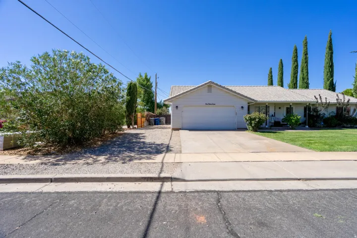 Single-story residence featuring an attached garage, paved driveway, and established front landscaping