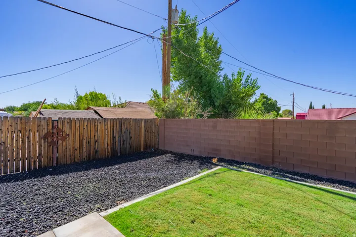 Expansive outdoor area featuring a manicured lawn, decorative black rock landscaping, and a wood privacy fence