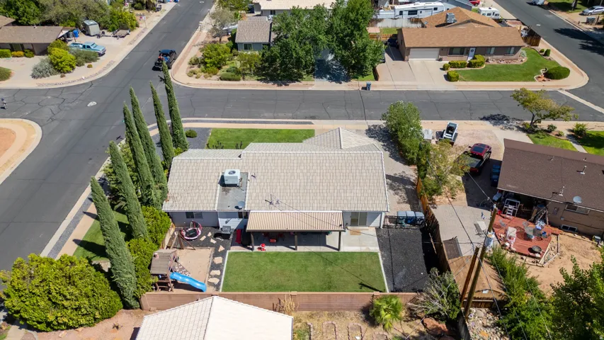 Expansive backyard featuring a manicured lawn, covered patio, and established landscaping
