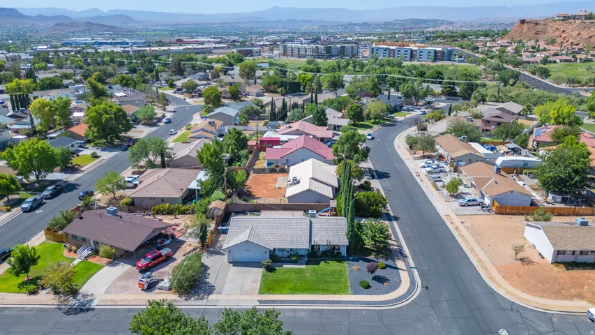 Overhead perspective of a residential neighborhood featuring paved streets, mature trees, and distant hills
