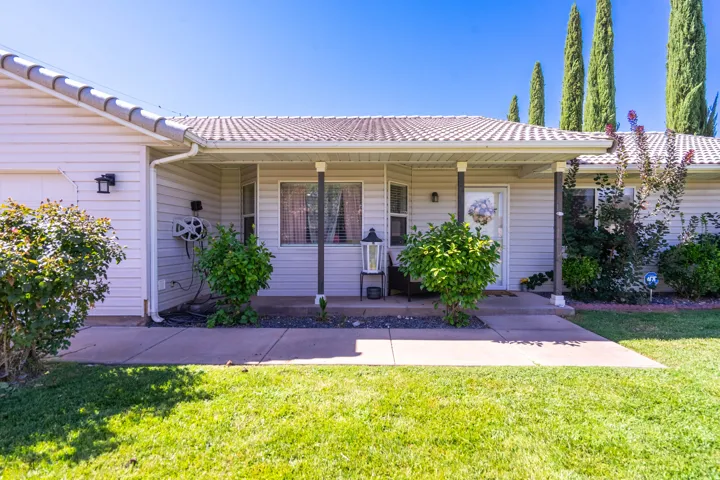 Covered front porch with dark support columns, light-colored siding, and a tiled roof