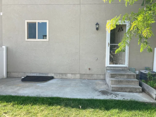 Concrete patio with a concrete staircase leading to an exterior door