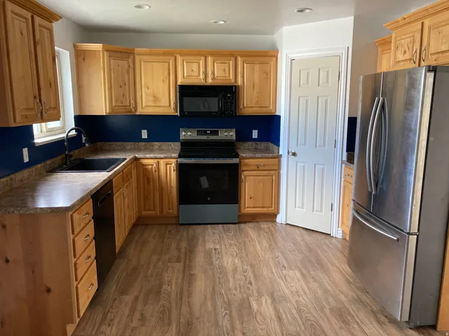 Kitchen featuring wood-finish cabinetry, dark countertops, and a full suite of stainless-steel appliances