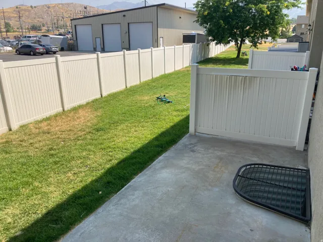 Concrete patio area with a white privacy fence
