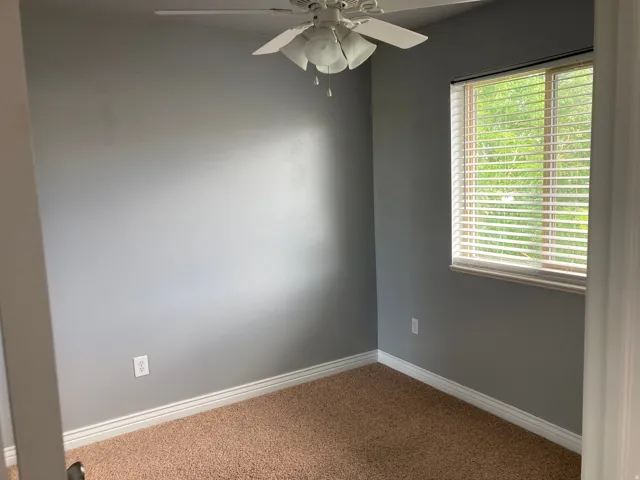 Neutral gray walls with white trim, a ceiling fan with integrated lighting, and a window featuring horizontal blinds