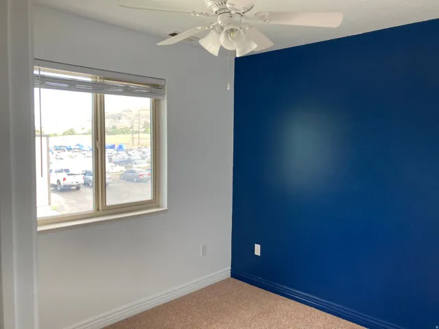 Window with blinds, ceiling fan, and blue accent wall