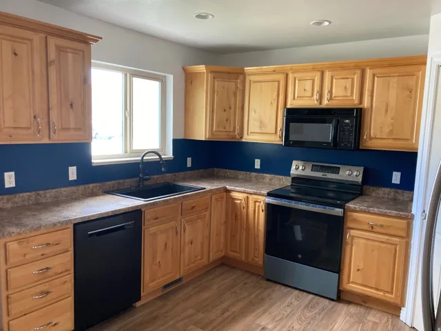Wood-finish flooring, recessed lighting, wood cabinetry, built-in dishwasher, and a stainless steel and black range