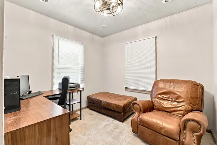 Recessed lighting fixtures, ceiling-mounted light fixture, two windows, wall-to-wall carpeting, wood-finish desk