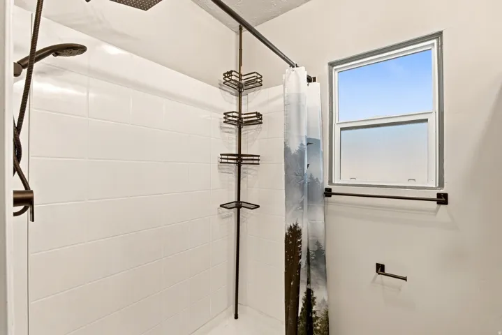 Tiled shower enclosure with dark bronze fixtures and a built-in corner shelf system