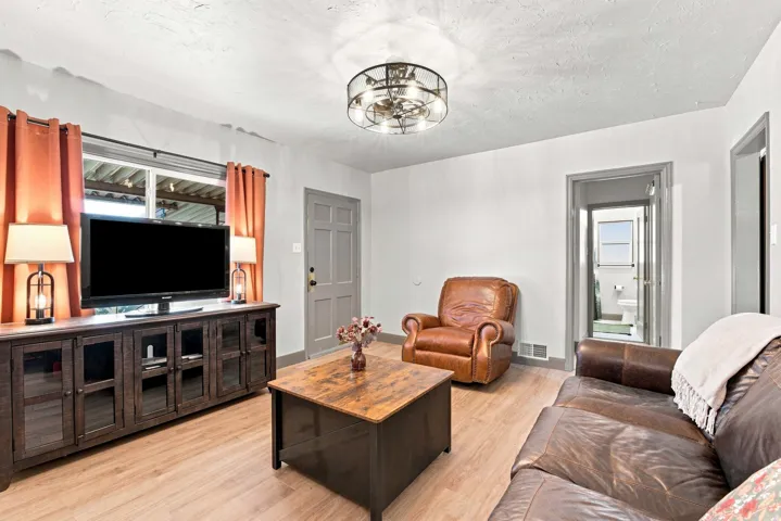 Neutral wall tones, wood-finish flooring, ceiling-mounted light fixture, and a paneled entry door