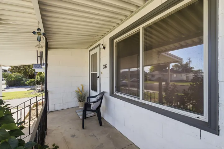 Covered front porch featuring a white screen door and a large picture window with dark trim