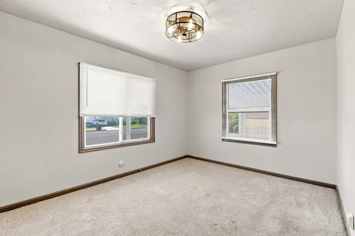 Neutral wall finishes, textured ceiling, two windows with blinds, and a semi-flush mount ceiling light