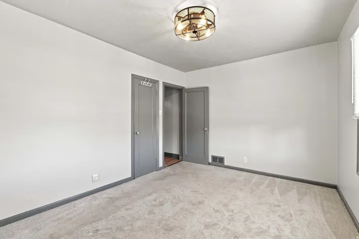 Light gray carpeting, white painted walls, and a contemporary ceiling light fixture