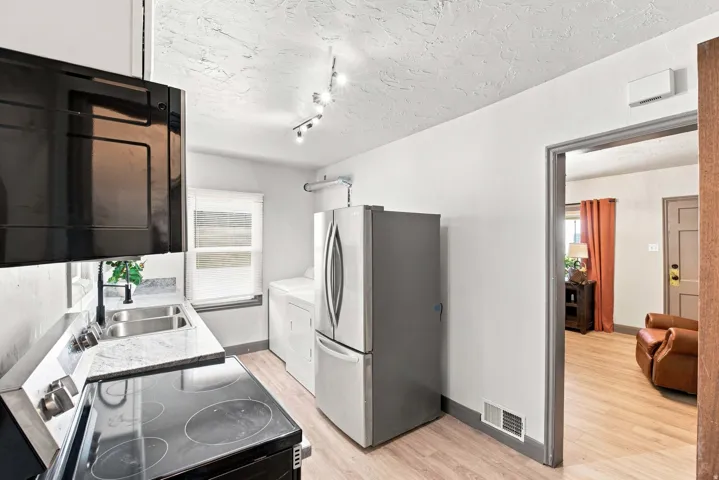 Kitchen featuring a double basin sink, solid surface countertops, and wood-finish flooring