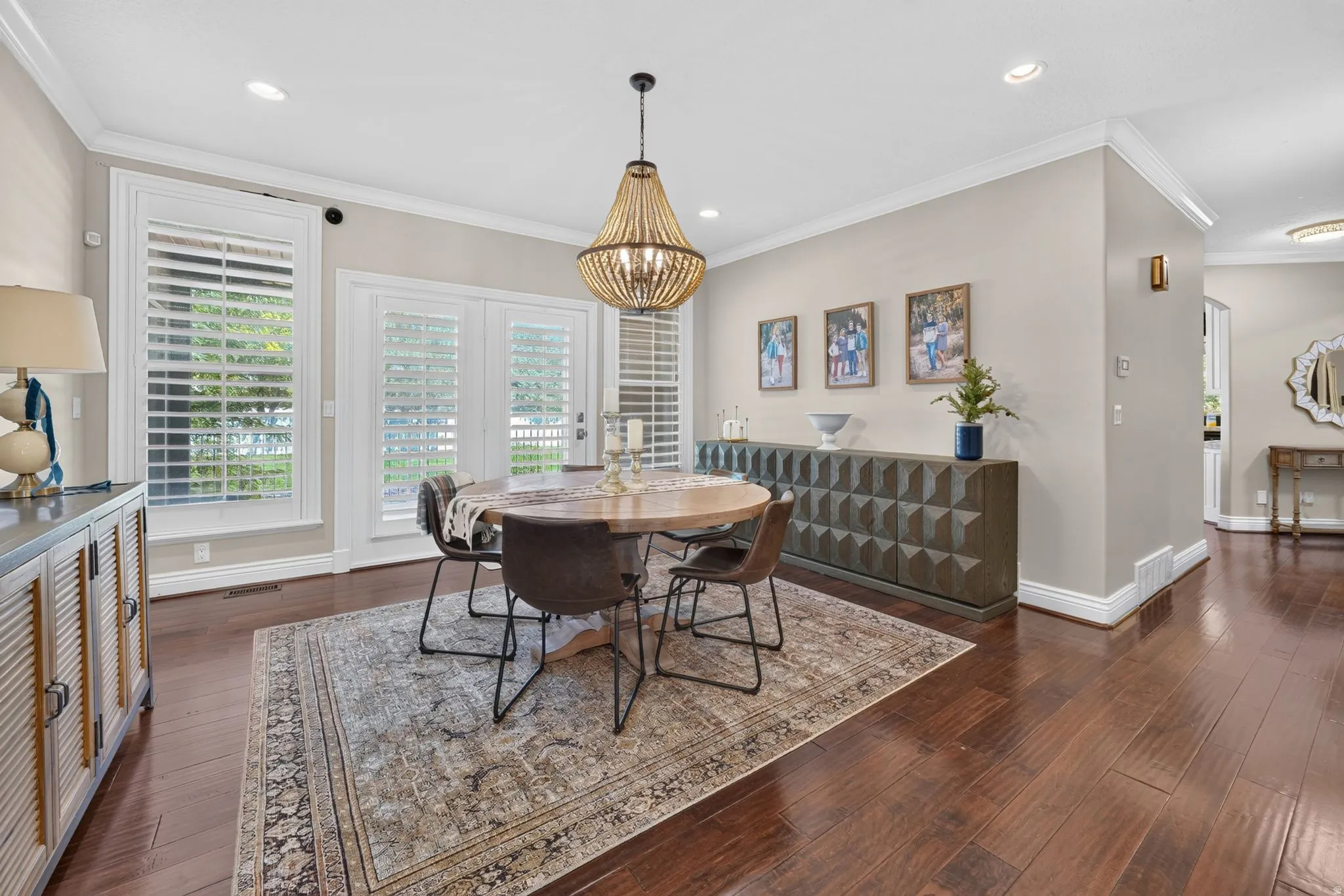 Hardwood flooring, white plantation shutters, crown molding, double patio doors, and recessed lighting