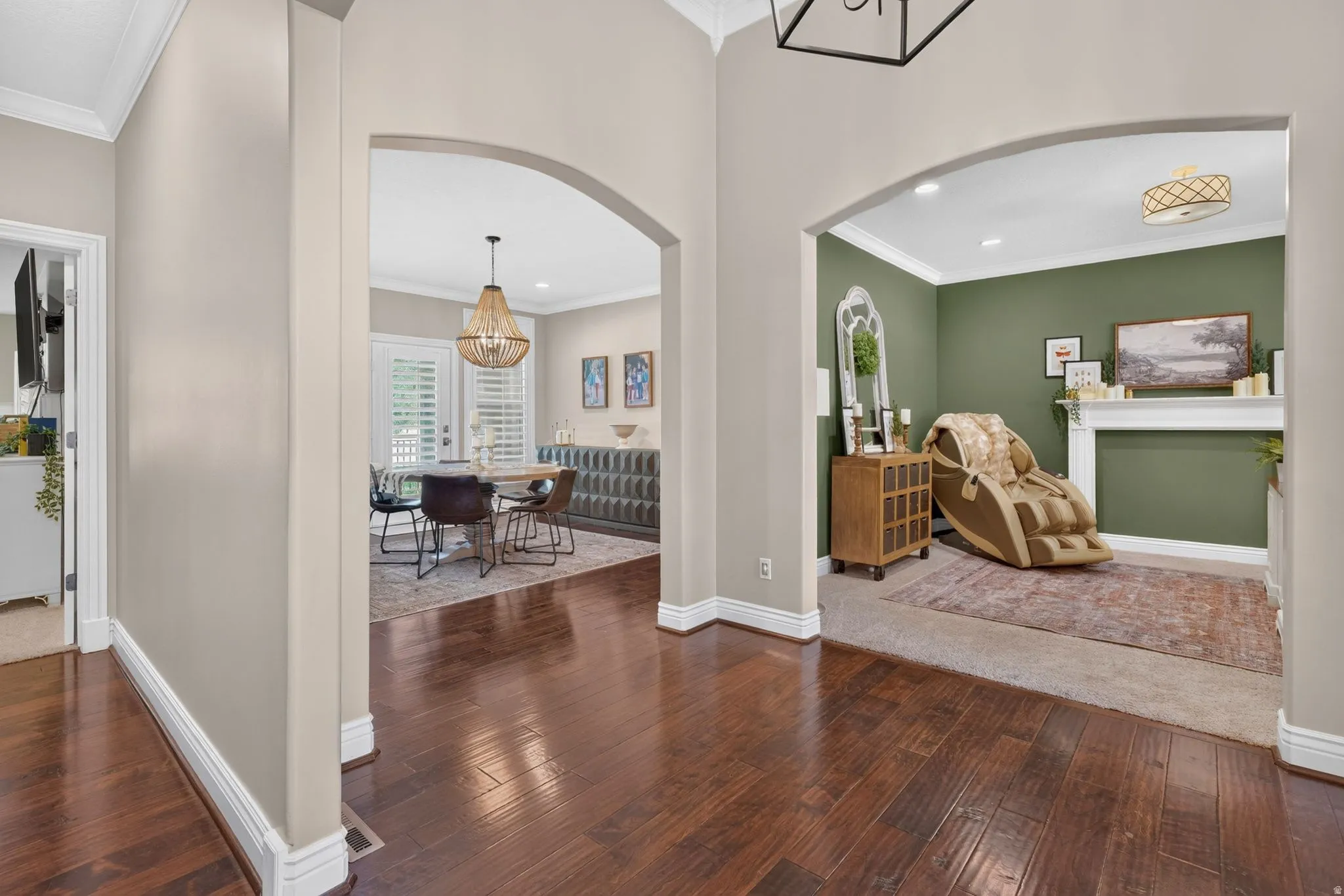 Hardwood flooring, arched doorways, crown molding, fireplace mantel, and recessed lighting