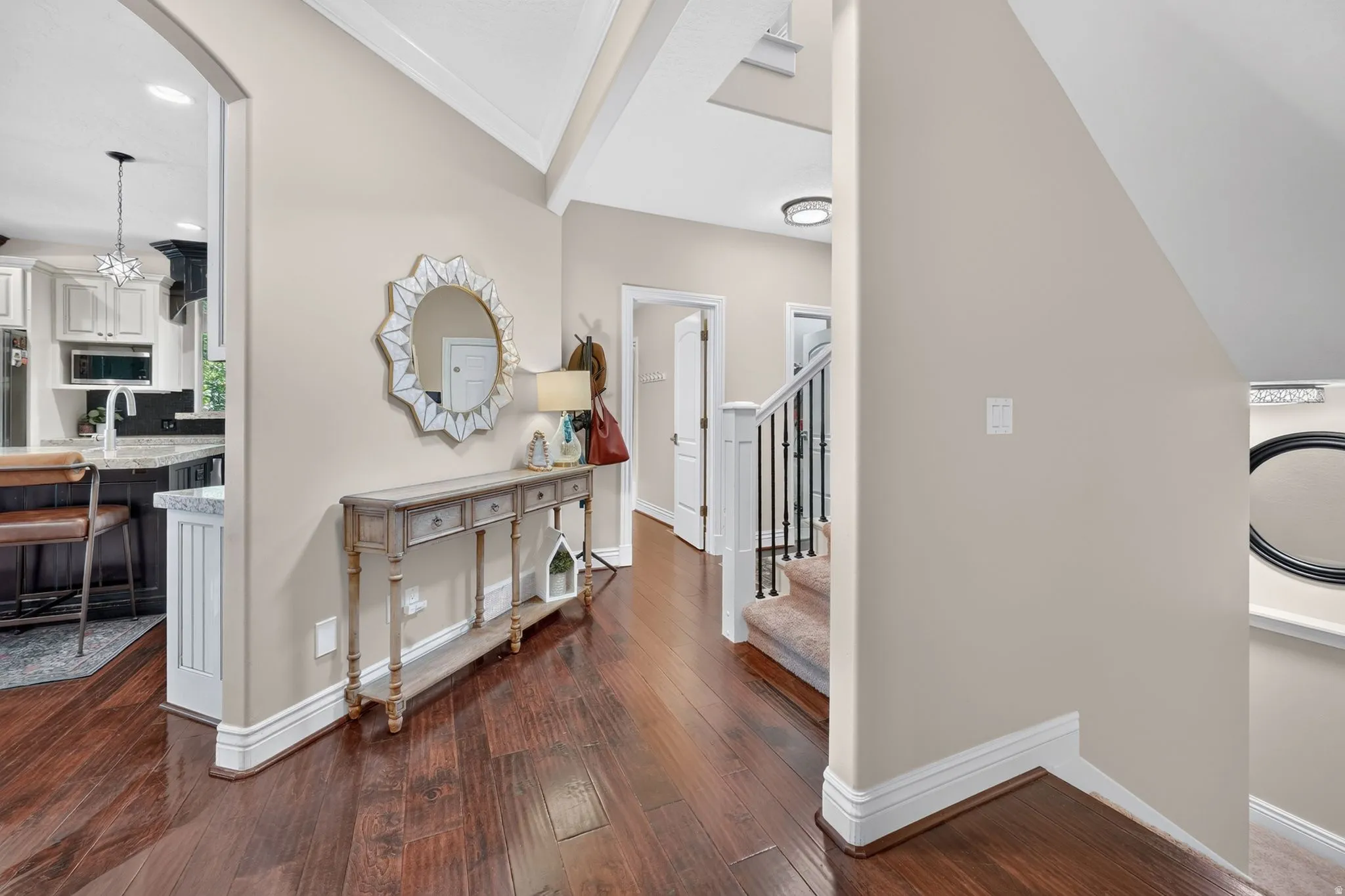 Elegant foyer showcasing soaring vaulted ceilings with skylight, rich wood-finish flooring, and decorative console table with ornate mirror