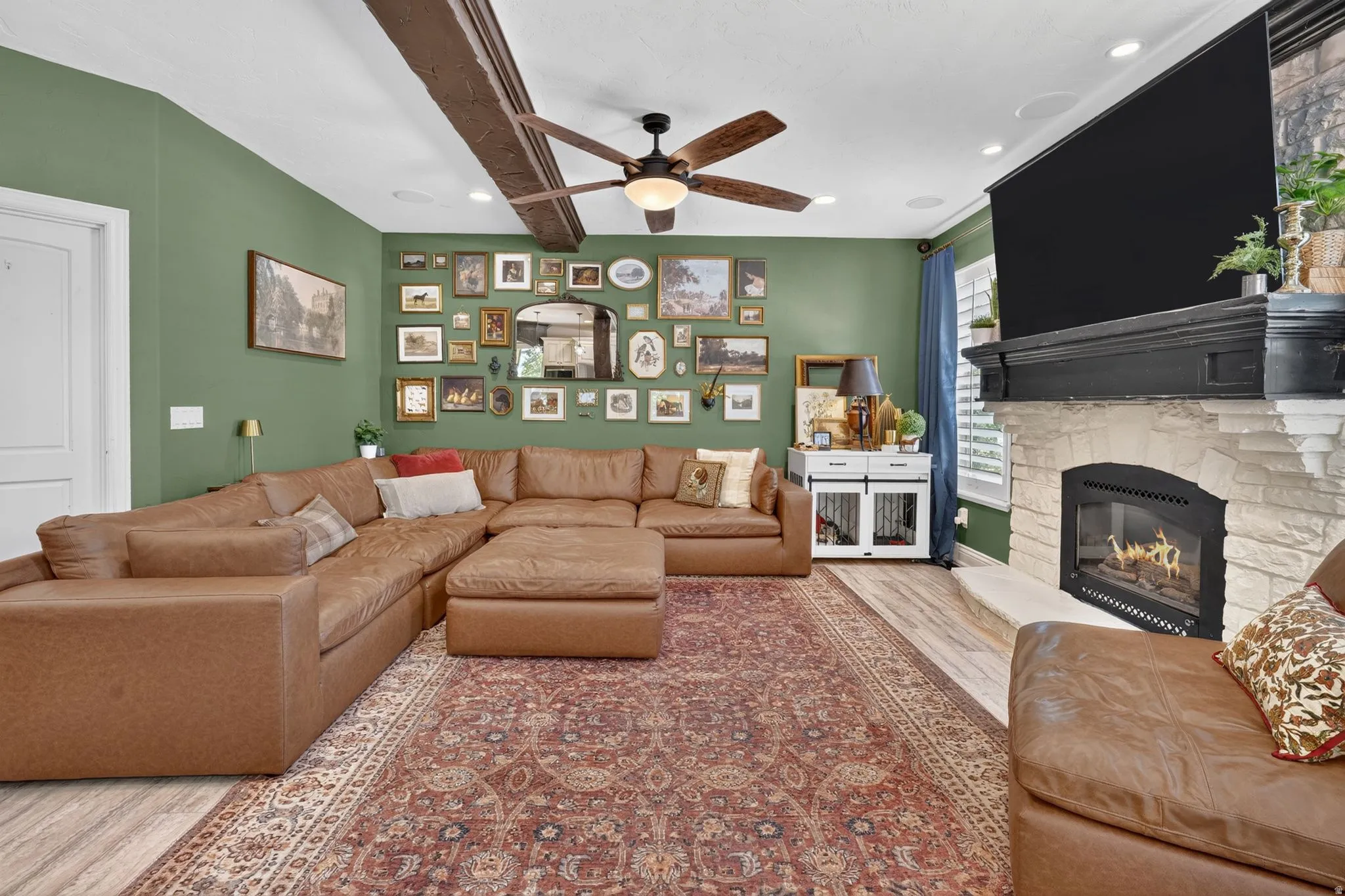 Fireplace with a stone surround and mantel, wood-finish flooring, and recessed lighting