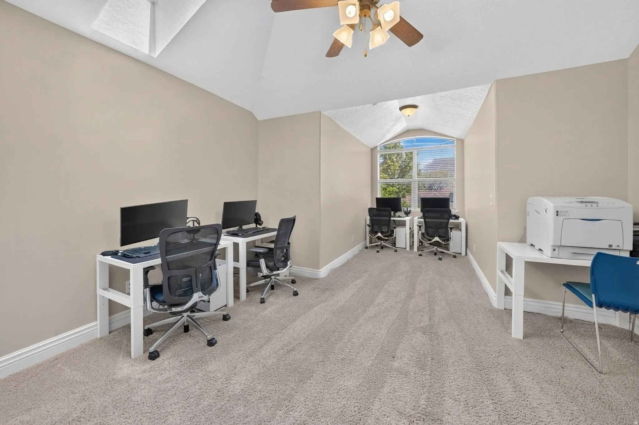 Carpeted room with vaulted ceiling and a ceiling fan light fixture