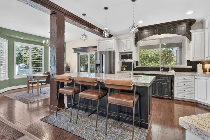 Kitchen featuring an expansive island with a light-toned countertop, wood-finish flooring, two-tone cabinetry, and a built-in microwave