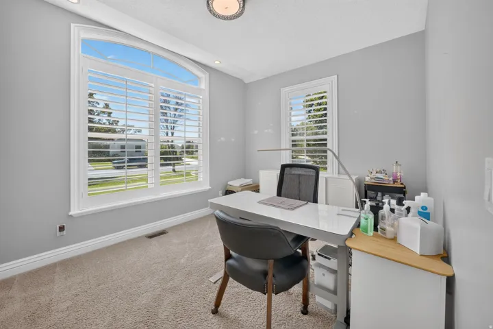 Arched window with plantation shutters, recessed ceiling lighting, and carpeted flooring