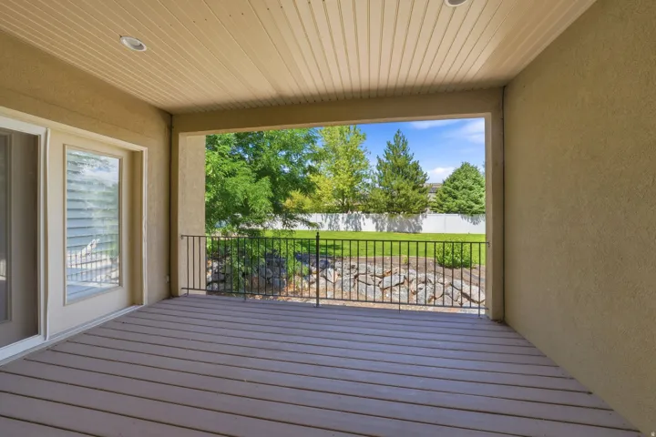 Covered patio with composite decking, recessed lighting, and a metal railing overlooking a landscaped area