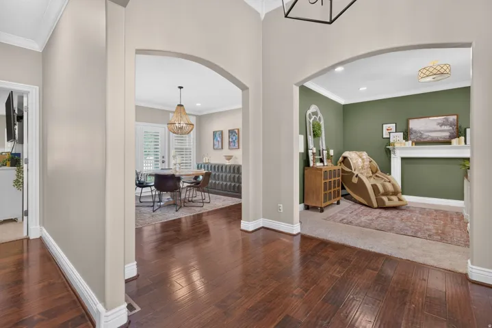Hardwood flooring, arched doorways, crown molding, fireplace mantel, and recessed lighting