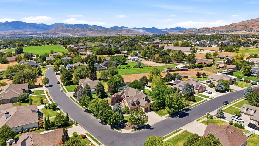 Residential neighborhood with mature trees, paved streets, and distant mountain backdrop