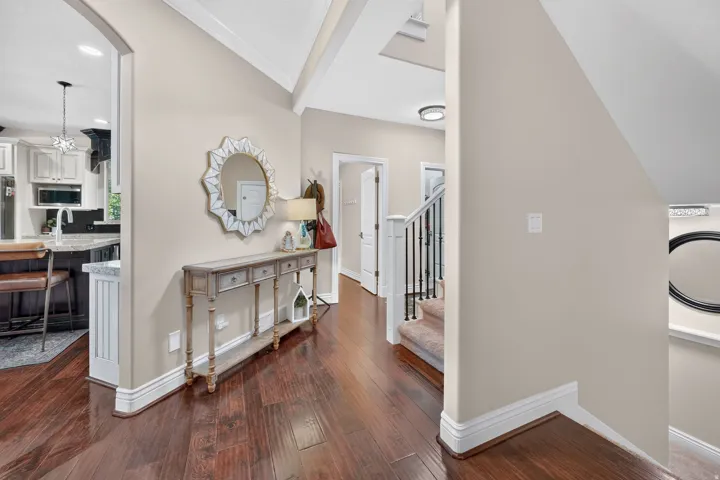 Elegant foyer showcasing soaring vaulted ceilings with skylight, rich wood-finish flooring, and decorative console table with ornate mirror