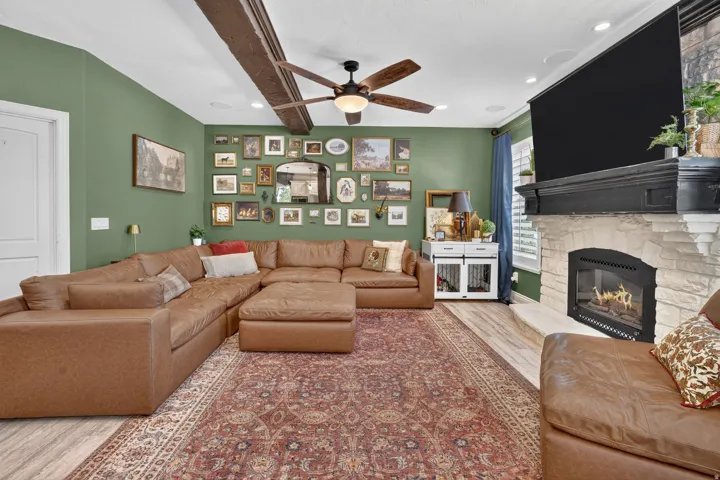 Fireplace with a stone surround and mantel, wood-finish flooring, and recessed lighting