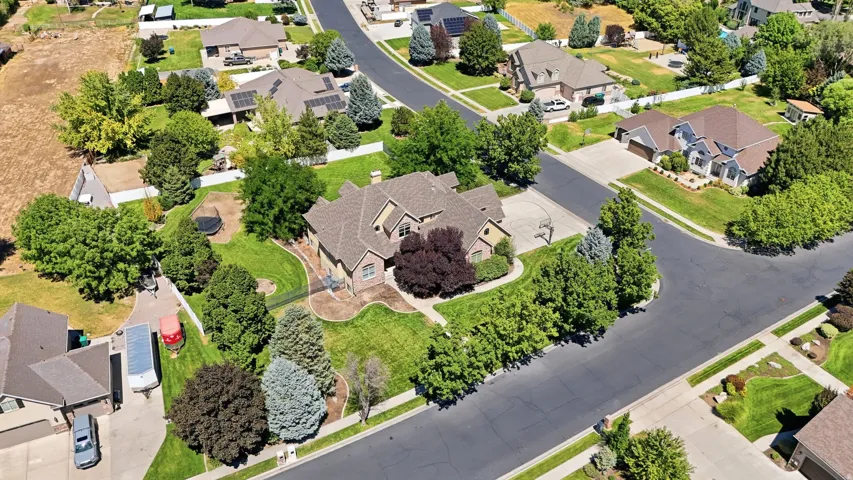 Expansive property featuring a multi-level roofline, brick facade, established landscaping, curved driveway, and a manicured lawn