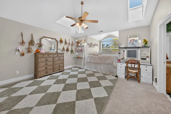 Vaulted ceiling, skylight, ceiling fan, arched window, and built-in desk unit