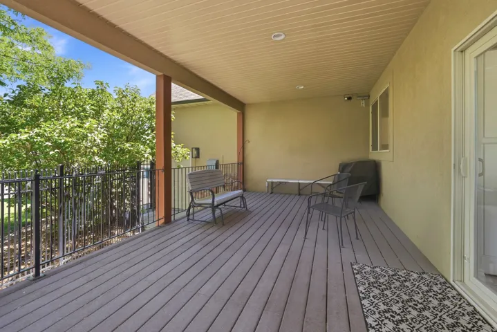 Covered deck with composite decking, recessed lighting, and a black metal railing