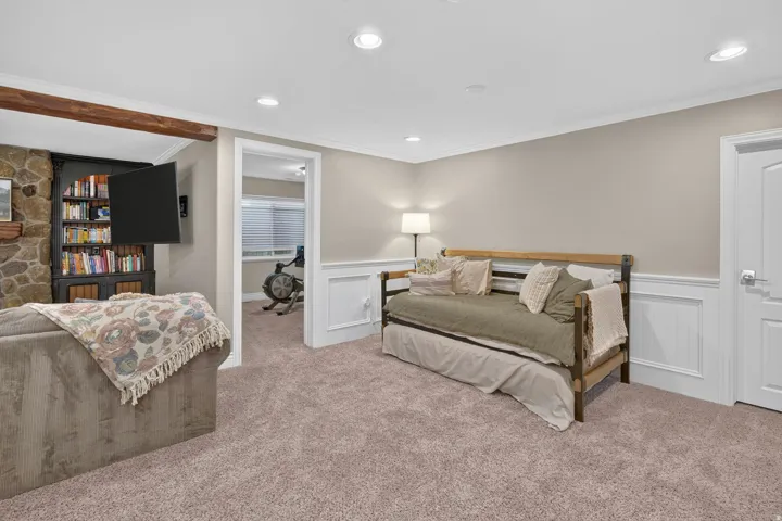 Recessed lighting, crown molding, wall paneling, built-in shelving, and stone surround fireplace