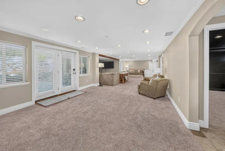 Spacious room featuring neutral carpeting, recessed lighting, and white trim