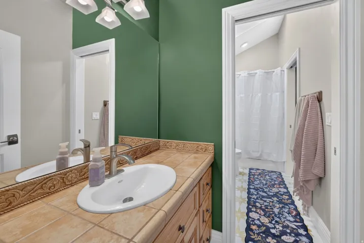 Bathroom vanity with a tiled countertop, undermount sink, and brushed nickel faucet