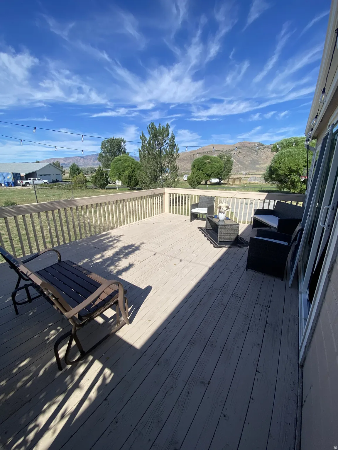 Expansive wood-finish deck with a wood railing and string lighting