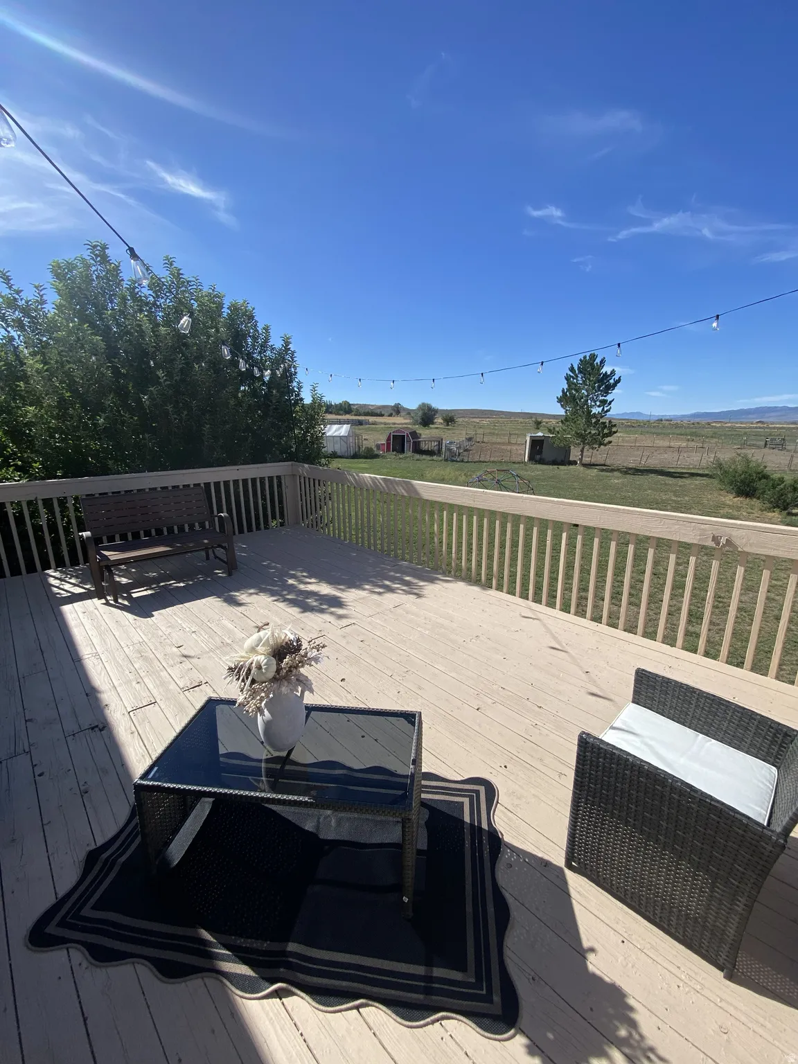 Expansive wood-finish deck with railing, string lighting, and direct outdoor access