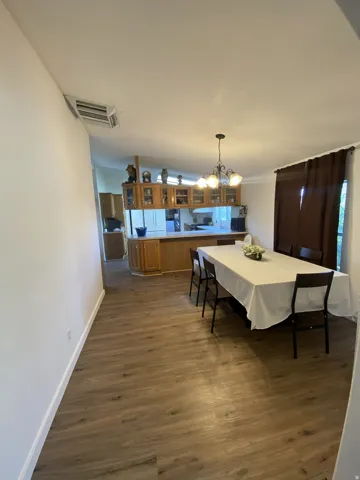 Wood-finish flooring throughout, with a built-in kitchen island featuring wood cabinetry and glass-front upper cabinets