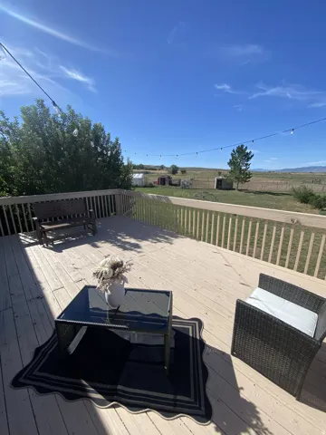 Expansive wood-finish deck with railing, string lighting, and direct outdoor access