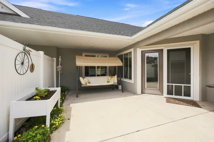 Covered patio with a concrete surface, white vinyl fencing, and multiple windows