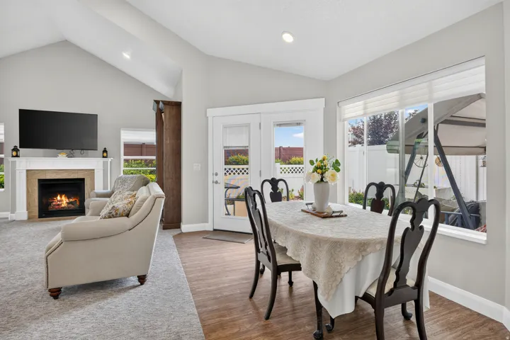 Vaulted ceilings, a built-in fireplace with mantel, French doors, large windows, and wood-finish flooring