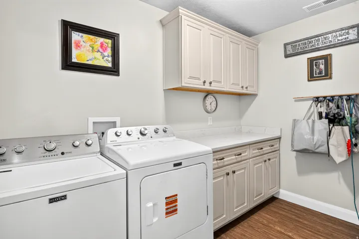 Custom cabinetry with ample storage, expansive countertop space, wood-finish flooring, and crown molding