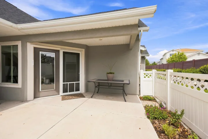Covered patio, sliding glass door, white lattice fencing, and stucco exterior