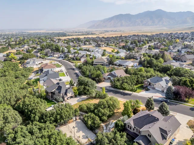 Residential neighborhood with established homes, mature trees, mountain backdrop, and paved streets