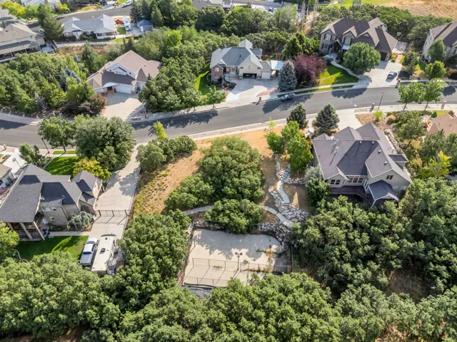 Expansive property with mature trees, a multi-level stone pathway, and a recreational court