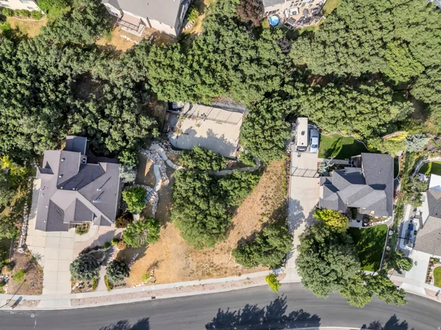 Manicured property with mature trees, paved driveways, and sloped terrain