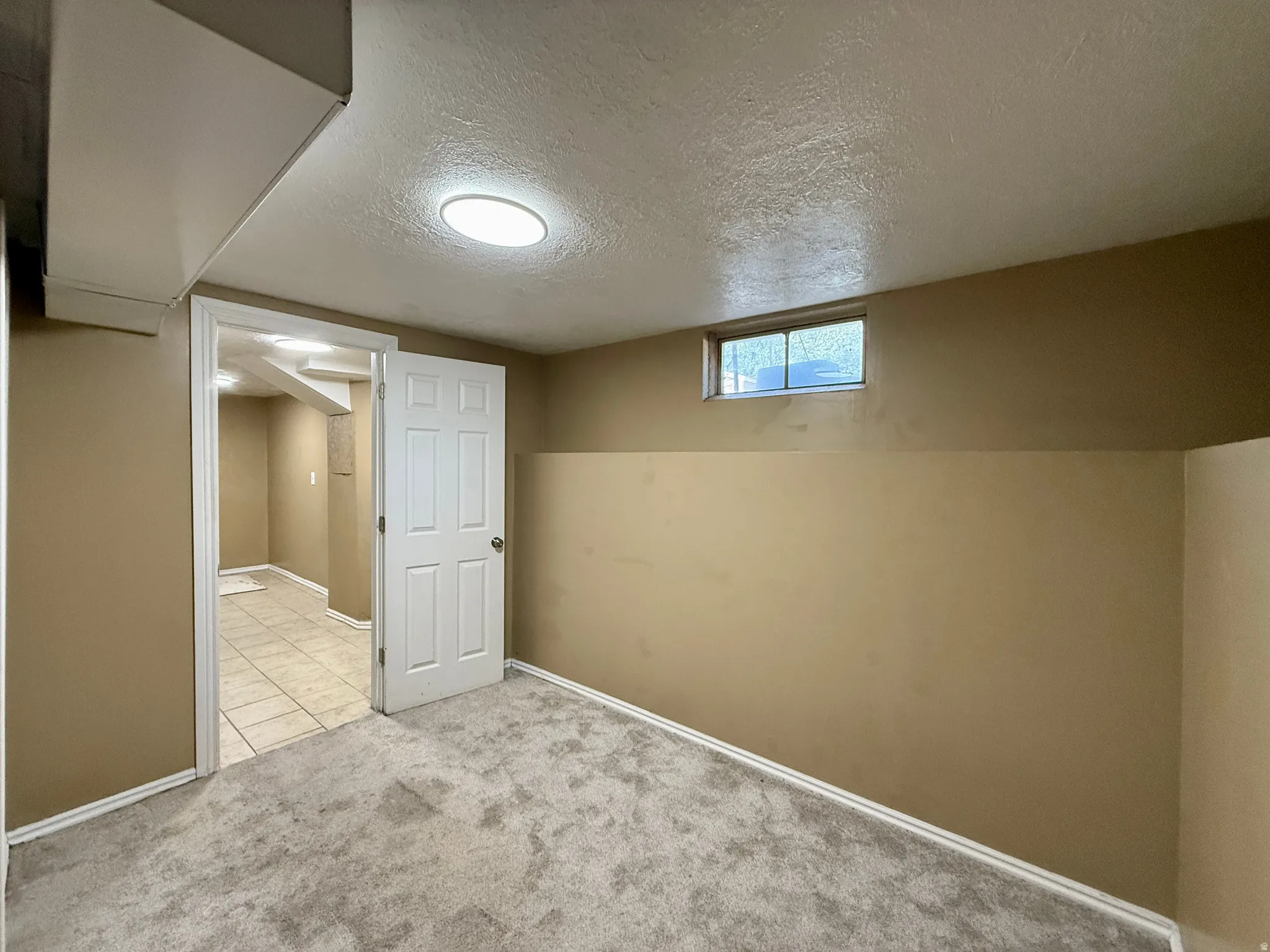 Carpeted flooring, neutral wall tones, recessed lighting, white trim, and a high window