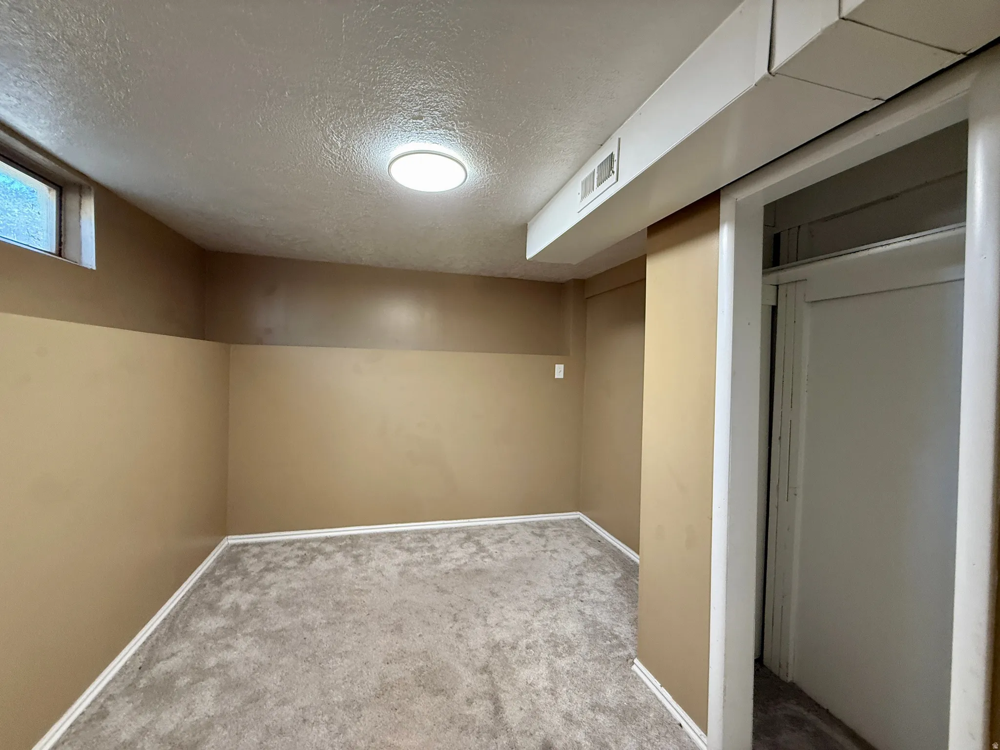 Carpeted flooring, neutral wall tones, recessed ceiling light, window, and white trim details