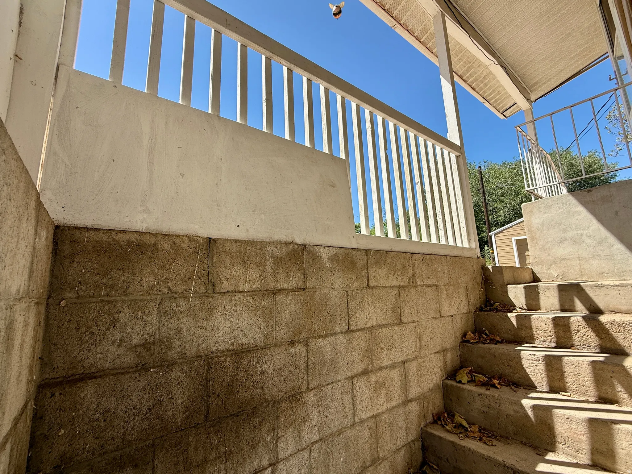 Concrete block foundation with a white painted porch railing and concrete steps